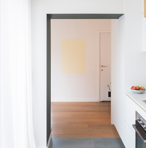 Minimalist kitchen entrance with white cabinets, wood flooring, and soft natural lighting – remodeling by Becker Services.