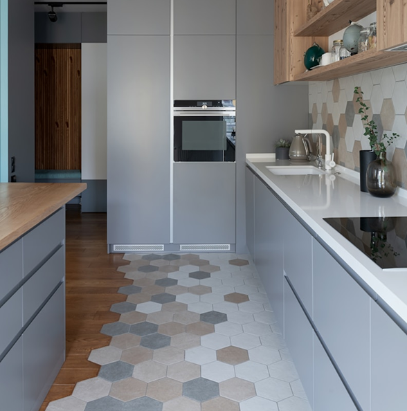 Modern kitchen remodel by Becker Services featuring hexagonal tile flooring blending into wood, flat-panel cabinetry, and clean white countertops.